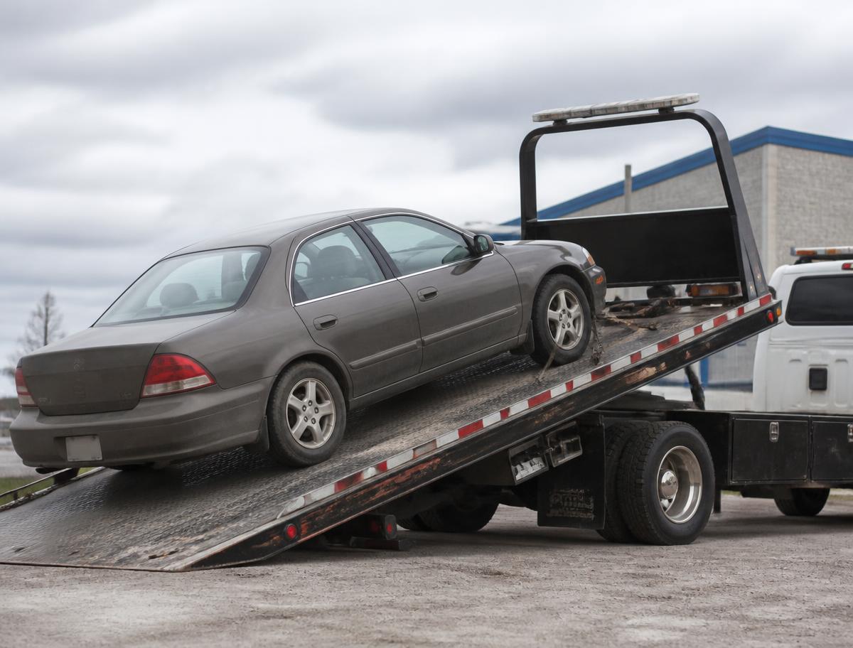 Sedan being winched up onto an angled flatbed tow truck deck